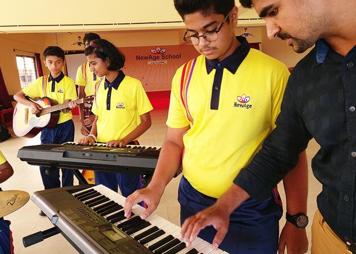 Teacher teaching harmonium to students during a music class at NewAge World School