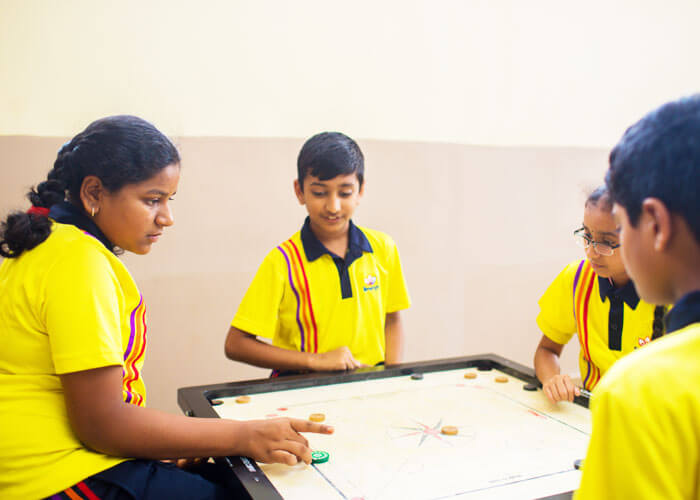 Students playing carrom and developing concentration and strategic skills at NewAge World School