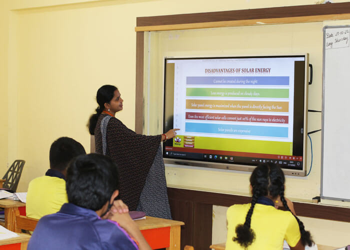 Teacher explaining solar energy concepts to students in a smart classroom at NewAge World School.