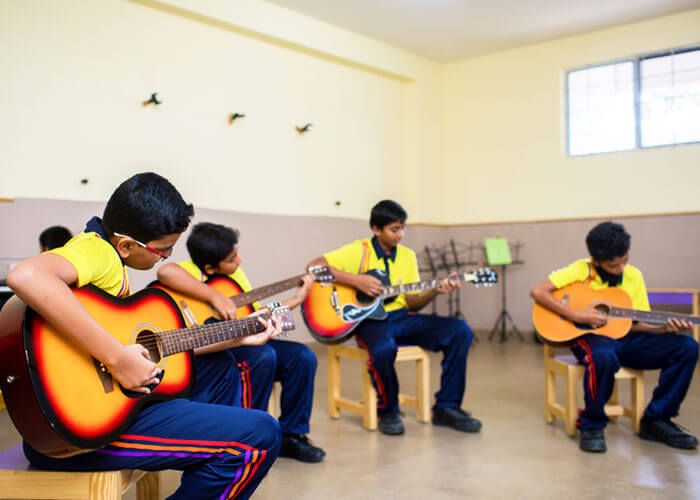 Students practicing guitar in a music class at NewAge World School.