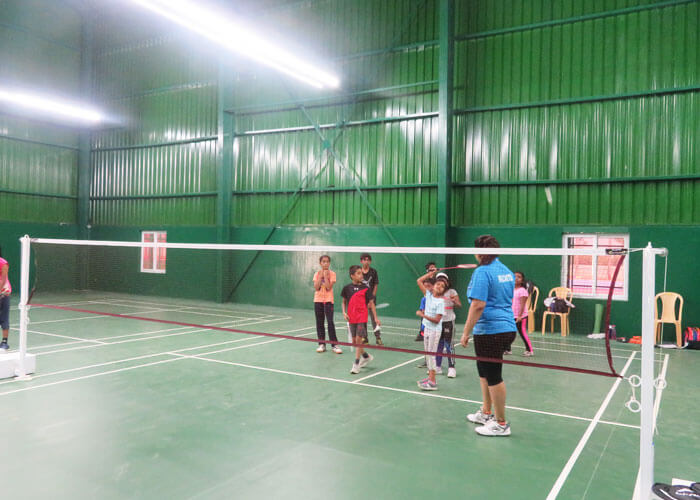 Students practicing badminton in the indoor sports facility at NewAge World School.